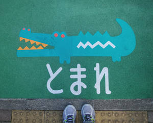 兒童運動鞋在鱷魚主題遊樂場標誌旁，帶有日文字元。