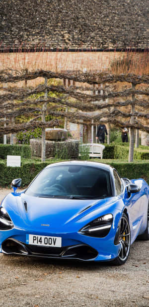藍色McLaren 720S停泊在葡萄園環境中，配有石頭建築。 — 藍色 壁紙
