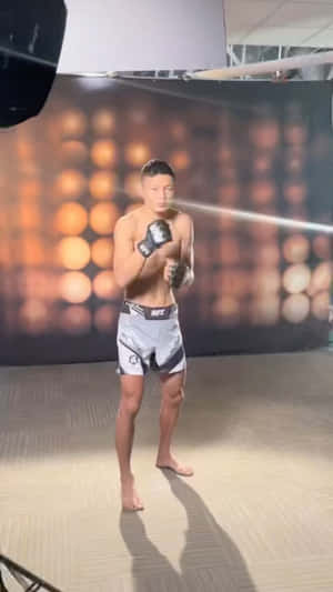 運動型戰士穿著UFC短褲和手套，在溫暖燈光的攝影棚中擺姿勢。