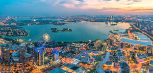 黃昏時分現代城市的鳥瞰圖，閃爍的建築物和一個大型湖泊。 — 天際線 壁紙