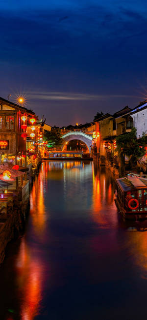 夜晚的運河，燈籠光芒和石橋倒映在水中。 — 唐人街 GIF 壁紙