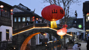傳統中國小鎮中，黃昏時被紅燈籠照亮的運河石橋。 — 唐人街 GIF 壁紙