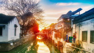夕陽下的運河，有傳統建築和石橋 — 唐人街 GIF 壁紙