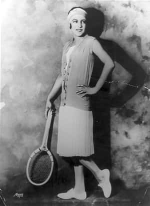 微笑的女性穿著1920年代網球服裝，在工作室肖像中手持球拍。 — 網球 壁紙