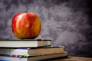 一個紅蘋果放在木質表面的一堆書上。 — 藝術 壁紙