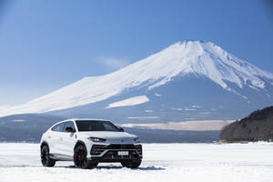 白色林寶堅尼 Urus 停在雪地上，背景是富士山。