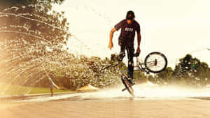 bmx車手在陽光明媚的公園跳過噴泉噴霧