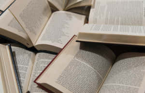 一堆打開的書籍，可見文字頁面和各種裝訂。 — 美學 壁紙