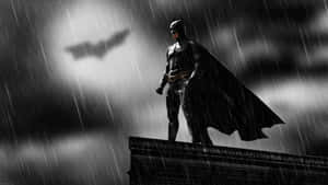 蝙蝠俠站在雨中屋頂上，背後有發光的蝙蝠標誌。