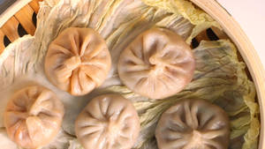 竹蒸籠內椰菜葉上的五個蒸餃。 — 中文 壁紙