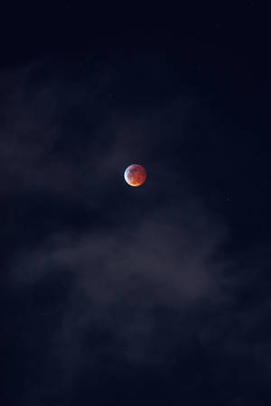 血月穿過暗夜雲層升起，星光可見。