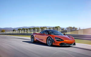 橙色McLaren賽車在賽道上高速行駛，背景模糊。 — 4K 法拉利 壁紙