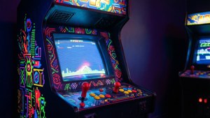 在黑暗房間中帶有發光按鈕和屏幕的復古街機。 — Outrun 壁紙