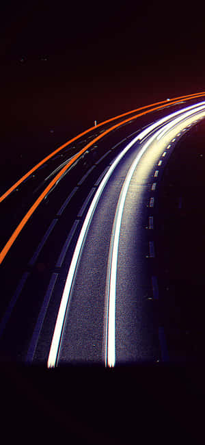 夜間黑暗蜿蜒道路上移動汽車產生的白色和橙色光條。