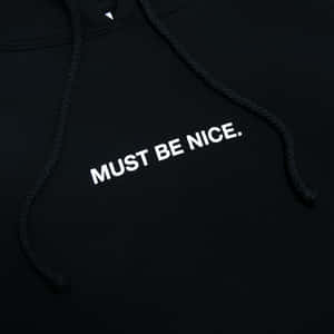 黑色連帽衛衣，白色刺繡文字寫著 MUST BE NICE。
