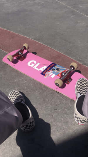 帶有「GLAT」標誌的粉紅色滑板和混凝土路面上的格仔鞋。 — 滑板 壁紙
