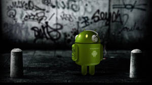 夜晚塗鴉小巷中的綠色Android吉祥物和混凝土護柱。 — 安卓 壁紙