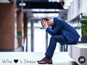 一名身穿藍色西裝的男子坐在長椅上，雙手抱頭，在辦公室裡顯得壓力很大。