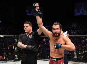 UFC拳手在八角籠內由裁判舉起手慶祝勝利。