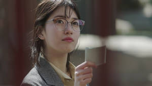 戴眼鏡的年輕女性在白天戶外拿著杯子。