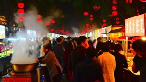 夜市街道，紅燈籠下，人們圍繞美食攤位，蒸汽升騰。