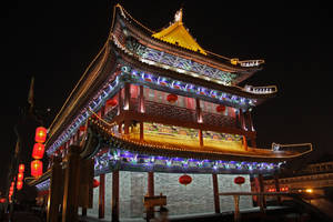 夜晚被紅色燈籠和燈串照亮的傳統中式門樓。 — 唐人街 GIF 壁紙