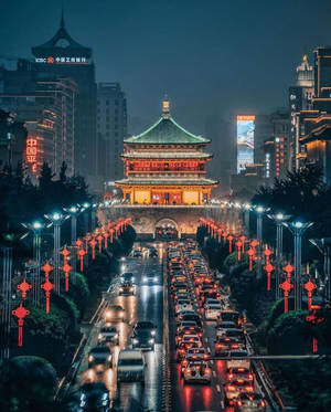 歷史悠久的中式塔樓夜景，掛著紅燈籠，交通繁忙。 — 4:5 壁紙