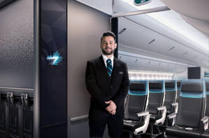 微笑的空中服務員穿著制服站在飛機客艙中，座椅帶有藍色裝飾。