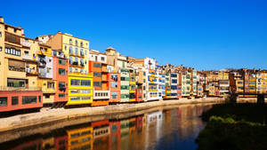 河邊色彩繽紛的建築物，藍天白雲，水面倒影。