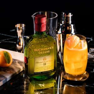黑色雲石吧枱上嘅 Buchanan's Deluxe 威士忌酒瓶同雞尾酒，配上橙裝飾。