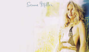 Sienna Miller 穿著帶有金色飾邊的白色連衣裙，站在陽光明媚的田野中。