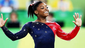 體操運動員Simone Biles身穿星條旗緊身衣，張開雙臂慶祝。