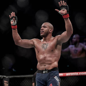MMA拳手在UFC八角籠中舉臂慶祝勝利。 — OLED 壁紙