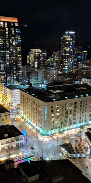 夜晚城市景觀，建築物燈火通明，街道繁忙。 — 18:9 壁紙