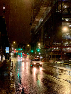 汽車在雨夜中沿著濕漉漉的城市街道行駛，路面有反射。