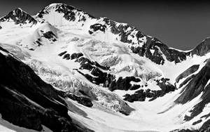 積雪的山峰，露出黑白岩石 formations。