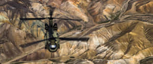 軍用直升機飛越一個有層狀岩層的峽谷。 — 直升機 壁紙