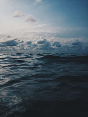 黃昏多雲的天空下深藍色的海洋波浪。