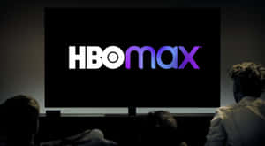人們在黑暗的影院中觀看大屏幕上的HBO Max標誌。