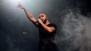 Drake 在煙霧彌漫的舞台上於聚光燈下對著麥克風唱歌。