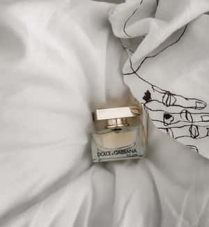 白色布料上的 Dolce & Gabbana 香水瓶與黑色手部圖案。