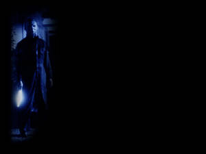 一個戴面具的恐怖角色在黑暗中手持發光的刀。