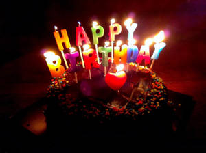 一個朱古力生日蛋糕，在黑暗的房間裡有點燃的蠟燭拼出 happy birthday。 — 生日蛋糕 壁紙