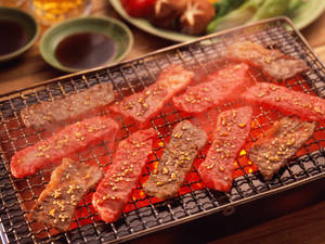 滋滋作響嘅牛肉同生肉喺烤架上，配上芝麻同配菜。