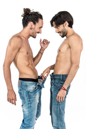 兩個赤膊上陣的男人穿著牛仔褲，在白色背景下笑著嬉戲互動。