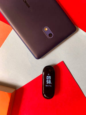 深紫色手機和黑色健身追蹤器在彩色幾何背景上。 — Nokia 壁紙