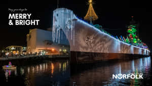 夜間節日燈光照亮的軍艦，水面倒影和節日裝飾。