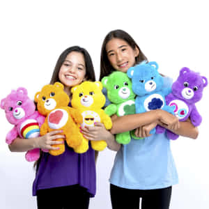 兩個女孩拿著色彩繽紛的Care Bears毛絨玩具，笑容燦爛。