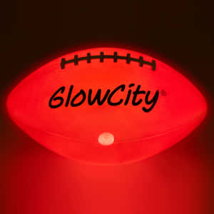 黑暗房間中帶有「GlowCity」標誌的紅色發光足球燈。 — iPad Pro 13 壁紙