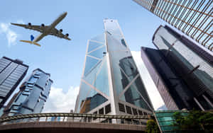飛機飛越城市中現代化的玻璃摩天大樓。 — 錢 壁紙